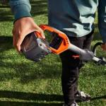 Man som håller i batteriet på en husqvarna grästrimmer.